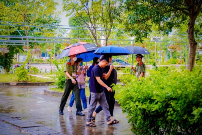 Học viên Trường Đại học Kỹ thuật-Hậu cần CAND hỗ trợ thí sinh vào điểm thi khi trời mưa.